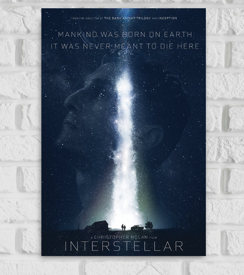Poster of the movie 'Interstellar' directed by Christopher Nolan, featuring a cosmic scene with a vertical beam of light extending from Earth into space, forming the silhouette of a man’s face. At the top, the quote reads: 'Mankind was born on Earth. It was never meant to die here.' Below, a farmhouse and two small human figures stand under a starry sky. The title 'INTERSTELLAR' appears at the bottom in sleek, futuristic font