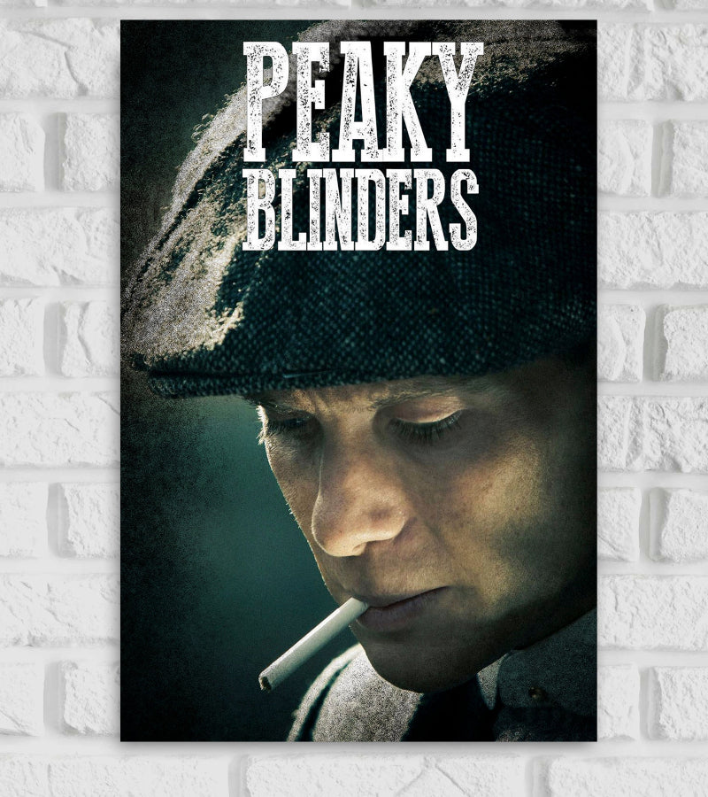Poster of the TV series Peaky Blinders featuring a close-up of a man wearing a flat cap, looking down pensively with a cigarette in his mouth. The background is dark and moody, matching the gritty tone of the series. The title 'PEAKY BLINDERS' is displayed in bold, distressed white text at the top of the image."