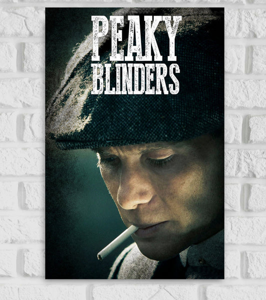 Poster of the TV series Peaky Blinders featuring a close-up of a man wearing a flat cap, looking down pensively with a cigarette in his mouth. The background is dark and moody, matching the gritty tone of the series. The title 'PEAKY BLINDERS' is displayed in bold, distressed white text at the top of the image."