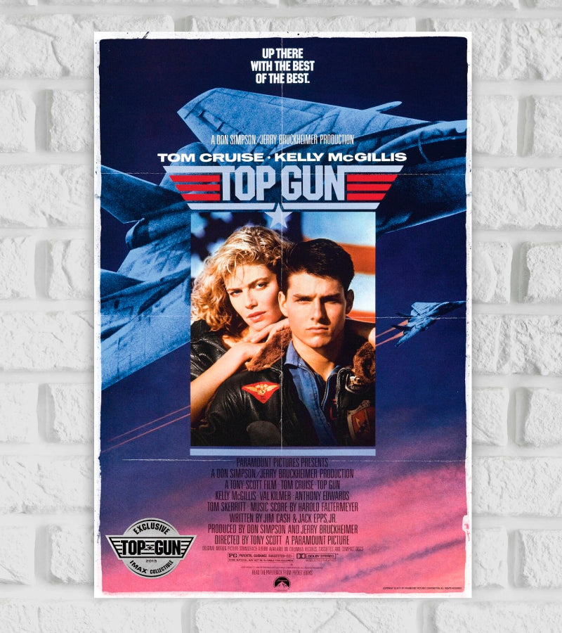 Poster of the Hollywood Actre Actress Movie Action adventure drama Romance Tom Cruise and Kelly McGillis. The background shows fighter jets in flight with a patriotic red, white, and blue color scheme. The text at the top reads "Up there with the best of the best." The title "Top Gun" is displayed prominently in the center with a star and wings emblem. At the bottom, production credits and a badge stating "Exclusive Top Gun IMAX Collector's Edition" are visible.