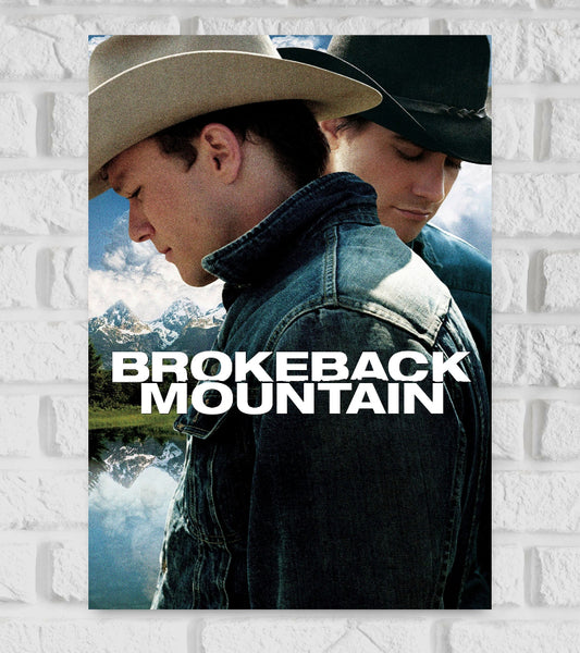 Poster of Brokeback Mountain featuring two men in cowboy hats and denim jackets standing close together with solemn expressions, set against a scenic background of mountains, trees, and a reflective lake. The title "Brokeback Mountain" is displayed in bold white letters across the center Hollywood Western  Romance romantic drama film directed by Ang Lee Linda Cardellini Actor Actress