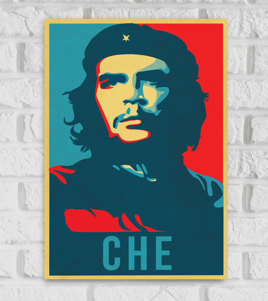 Pop art-style poster of Che Guevara featuring a bold, high-contrast color palette of red, yellow, blue, and teal. The portrait shows Che in his iconic look with a beret bearing a star, gazing into the distance with a serious expression. The background is split with vibrant red and teal, and the name "CHE" is written in large capital letters at the bottom