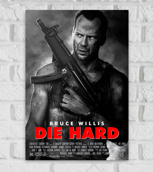 Poster for the action movie "Die Hard" featuring Bruce Willis. The image is in black and white, showing Bruce Willis as John McClane, bruised and intense, holding a large rifle over his shoulder. He wears a dirty tank top and has a focused, gritty expression. The movie title "DIE HARD" is displayed in bold red letters at the bottom, with "BRUCE WILLIS" written above it in white. Below the title are the film credits in small white text. The overall tone is dark and intense, reflecting the film's high-stakes 