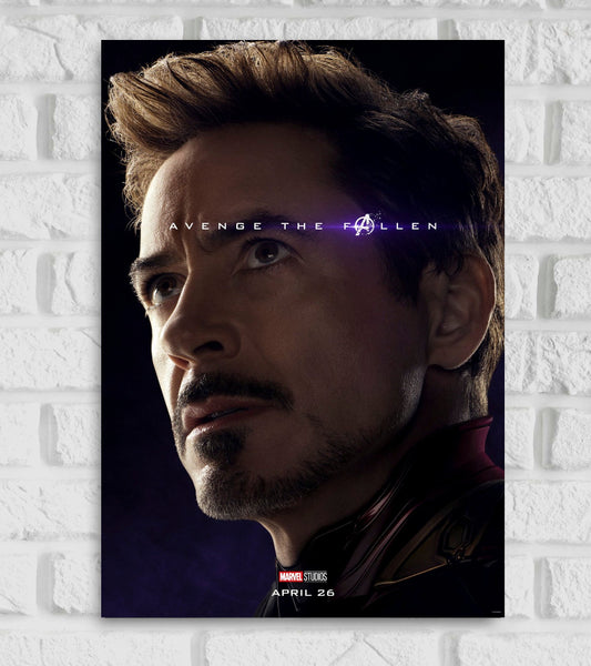 Poster of Iron Man Tony Stark from Marvel Studios promoting the film "Avengers Endgame" The image features a close-up of Tony Stark’s face portrayed by Robert Downey Jr. looking solemnly into the distance The background is dark emphasizing the dramatic lighting on his face Across the middle the tagline “AVENGE THE FALLEN” is displayed in bold white letters with a glowing purple highlight over the "A" symbol from the Avengers logo superhero persona of Anthony Edward " Tony " Stark Hollywood fiction Character